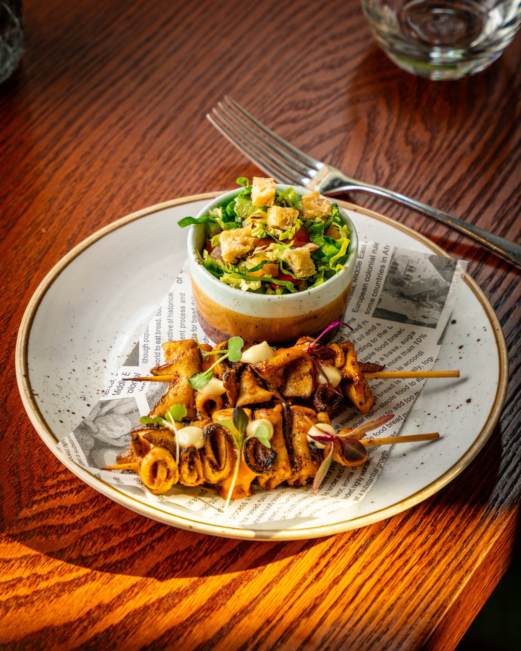 Close up of food on a plate with a bowl of salad