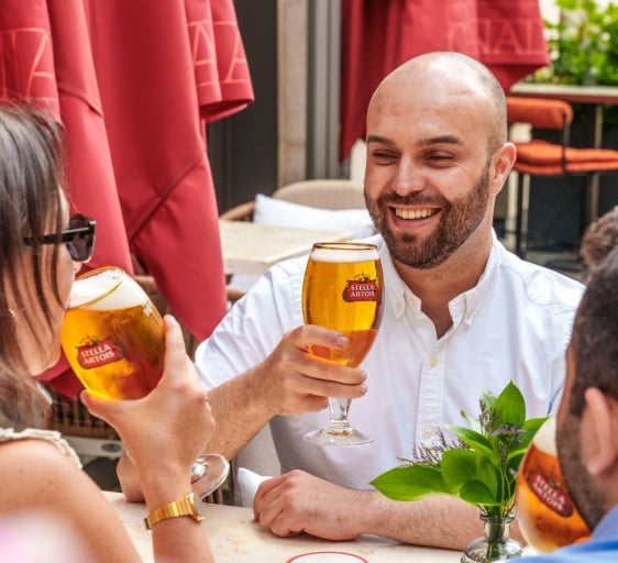 People sitting on the summer terrace drinking Stella Artois pints at The Cardinal Bar & Kitchen
