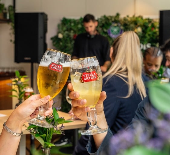 Two pints of Stella Artois cheersing in front of a live DJ
